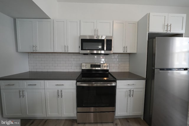 kitchen with white cabinetry, decorative backsplash, dark stone countertops, and appliances with stainless steel finishes