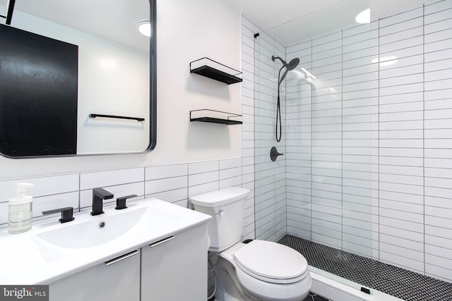 bathroom with toilet, tile walls, a tile shower, vanity, and decorative backsplash