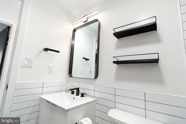 bathroom with vanity, toilet, and tile walls