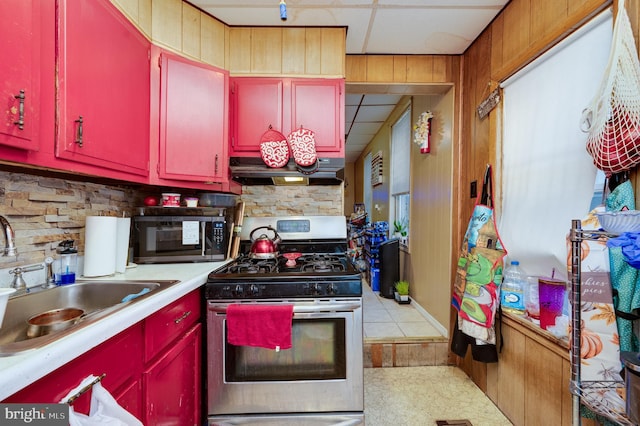 kitchen with sink, light tile patterned floors, appliances with stainless steel finishes, range hood, and a drop ceiling