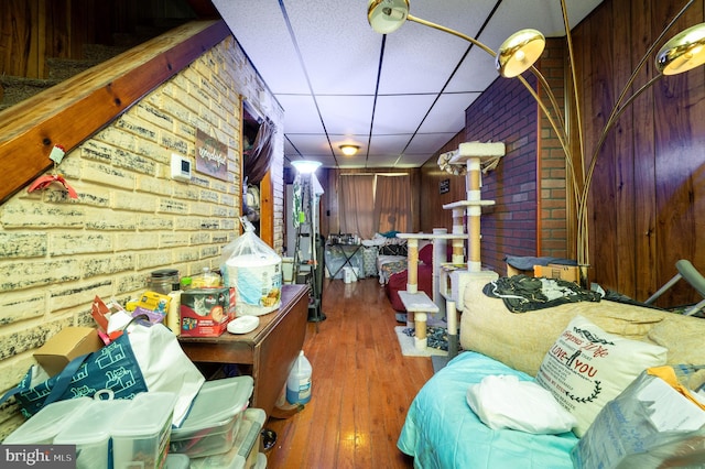 interior space featuring a paneled ceiling, brick wall, and hardwood / wood-style floors