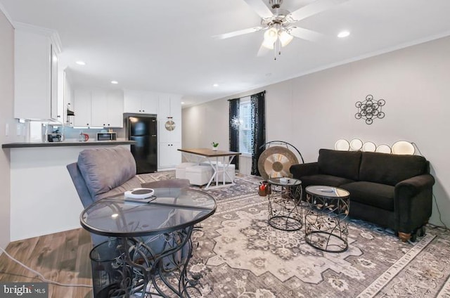 living room with ornamental molding, ceiling fan, and light wood-type flooring