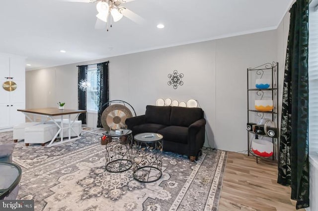 living room with crown molding, ceiling fan, and light wood-type flooring