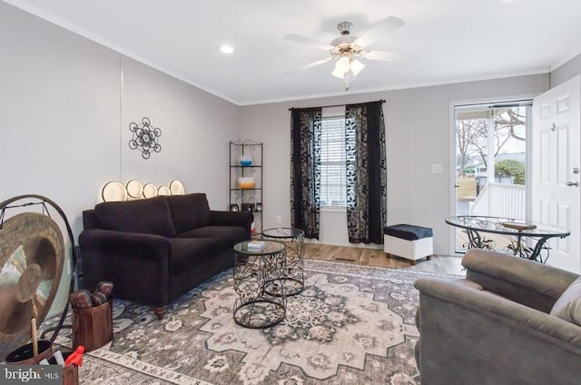 living room featuring hardwood / wood-style flooring, a wealth of natural light, ornamental molding, and ceiling fan