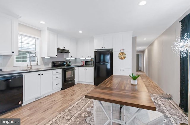 kitchen with light wood-type flooring, white cabinets, sink, and black appliances