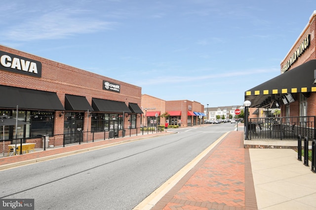 view of street featuring street lights, curbs, traffic signs, and sidewalks