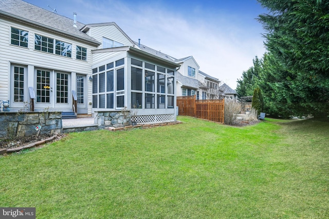 rear view of house featuring a sunroom and a lawn