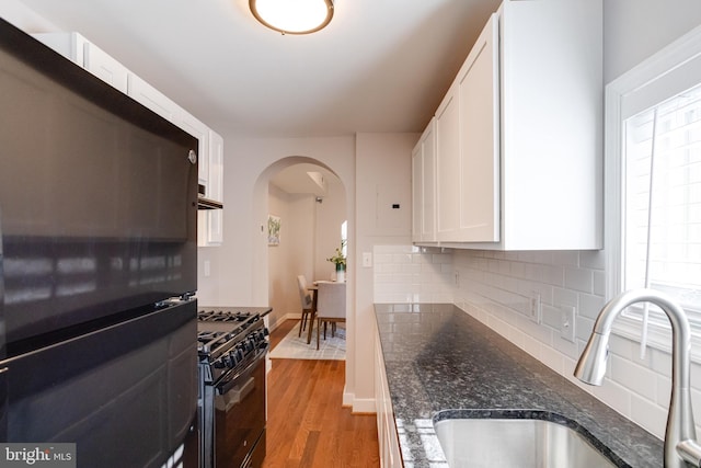 kitchen featuring sink, white cabinetry, tasteful backsplash, light hardwood / wood-style floors, and black appliances