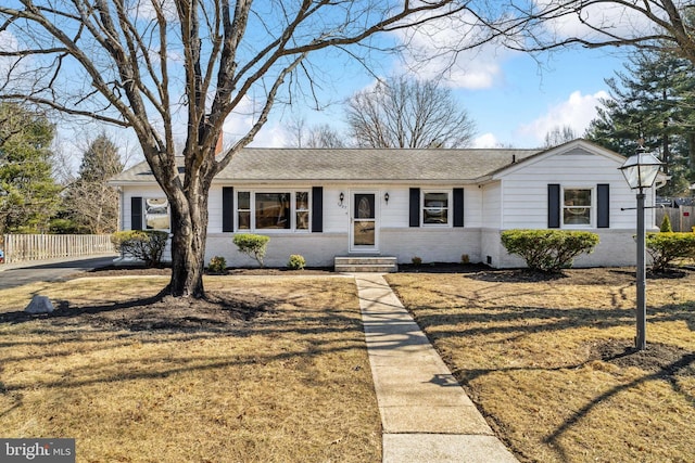 ranch-style home with entry steps, brick siding, fence, and a front lawn