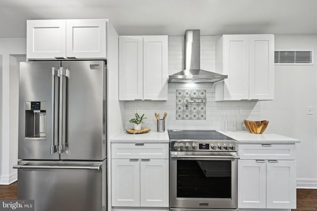 kitchen with white cabinetry, light stone countertops, wall chimney exhaust hood, and appliances with stainless steel finishes