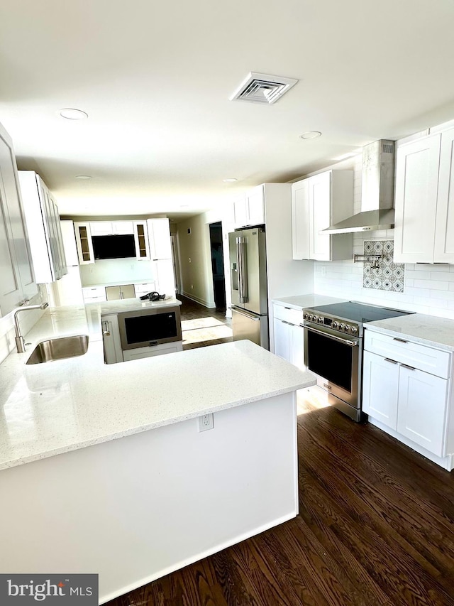 kitchen featuring sink, dark hardwood / wood-style floors, white cabinets, stainless steel appliances, and wall chimney range hood