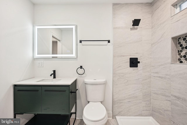 bathroom featuring vanity, toilet, and a tile shower