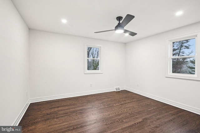 spare room with a wealth of natural light, dark wood-type flooring, and ceiling fan