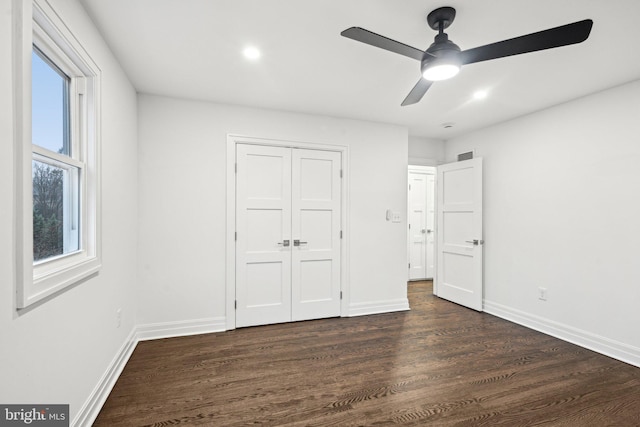 unfurnished bedroom with dark wood-type flooring, ceiling fan, and a closet