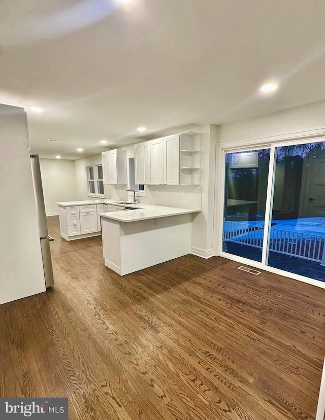 kitchen featuring sink, white cabinetry, fridge, dark hardwood / wood-style floors, and kitchen peninsula