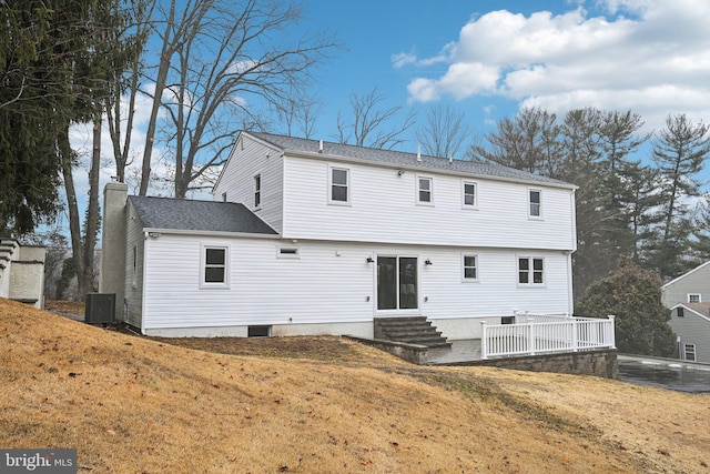 rear view of house featuring central AC and a lawn