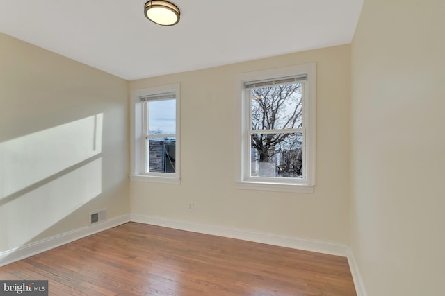 spare room with wood-type flooring and a wealth of natural light