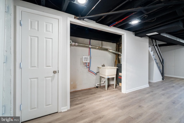 basement with sink and light hardwood / wood-style flooring