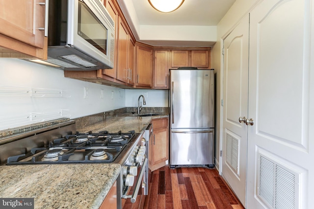 kitchen with dark wood-type flooring, stainless steel appliances, sink, and stone counters