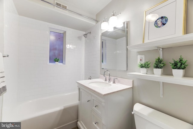 full bathroom featuring vanity, tiled shower / bath combo, and toilet