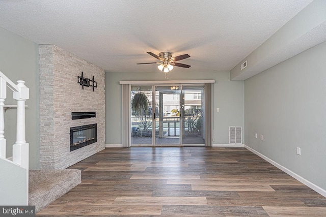 unfurnished living room with dark wood-type flooring, a textured ceiling, and a fireplace