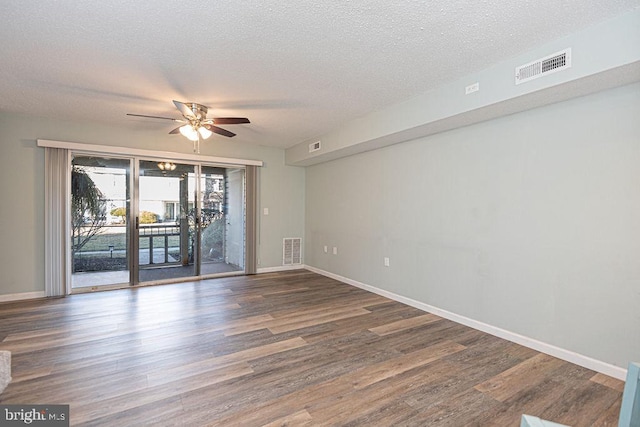 empty room with ceiling fan, dark wood-type flooring, and a textured ceiling