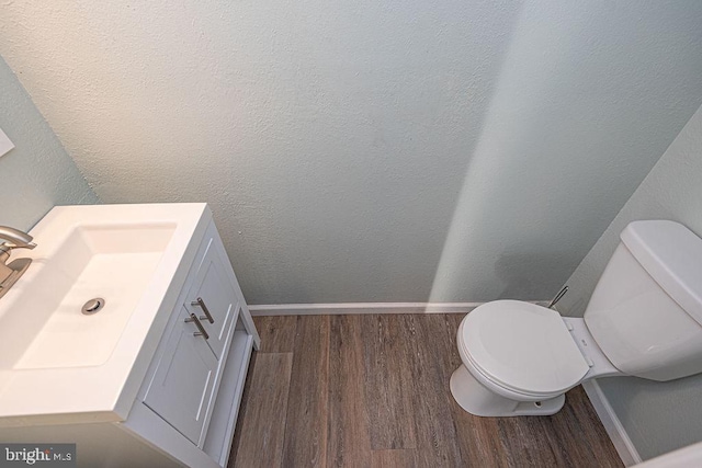 bathroom with vanity, toilet, and hardwood / wood-style floors