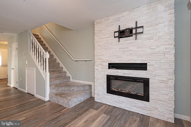 interior space with hardwood / wood-style flooring, a stone fireplace, and a textured ceiling