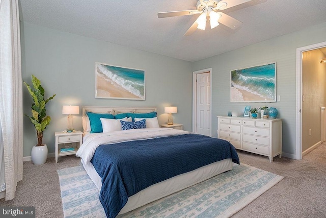 carpeted bedroom featuring ceiling fan and a textured ceiling