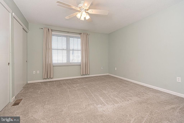 unfurnished bedroom with ceiling fan, a closet, a textured ceiling, and carpet