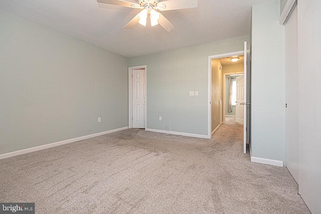 unfurnished bedroom with ceiling fan, light colored carpet, and a textured ceiling