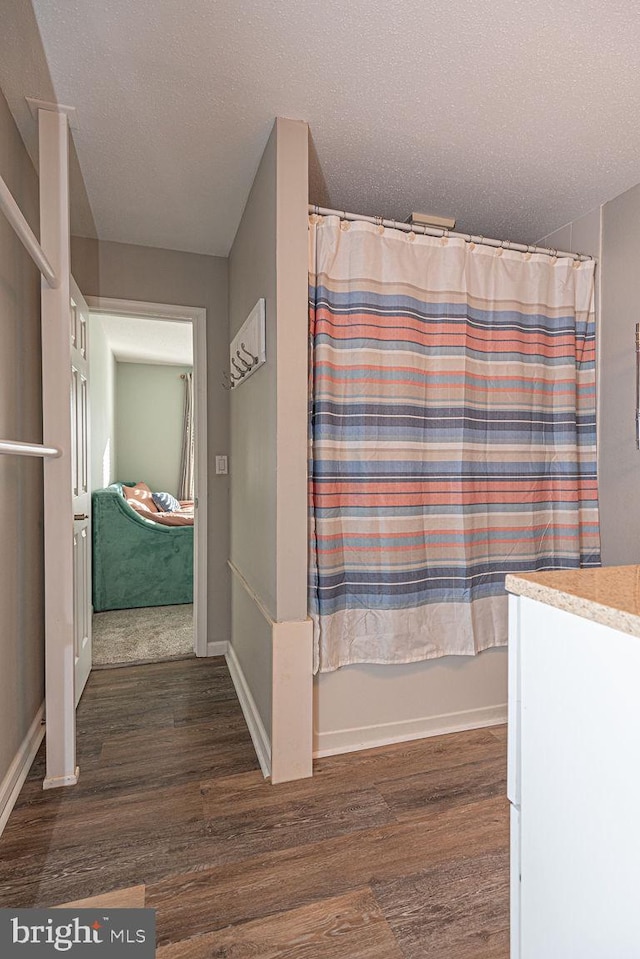 bathroom with hardwood / wood-style flooring, vanity, shower / tub combo, and a textured ceiling