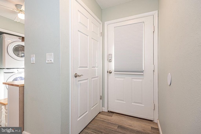 doorway with hardwood / wood-style flooring, ceiling fan, and stacked washer and clothes dryer