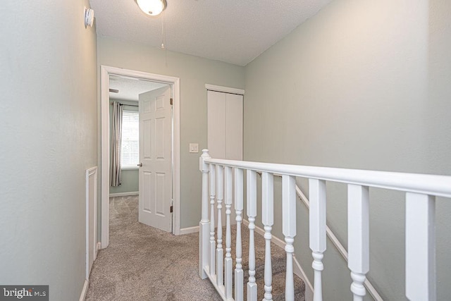 corridor featuring light carpet and a textured ceiling