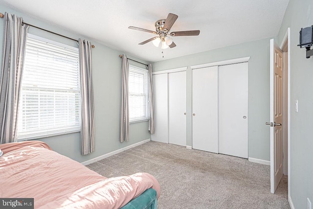 carpeted bedroom featuring two closets and ceiling fan