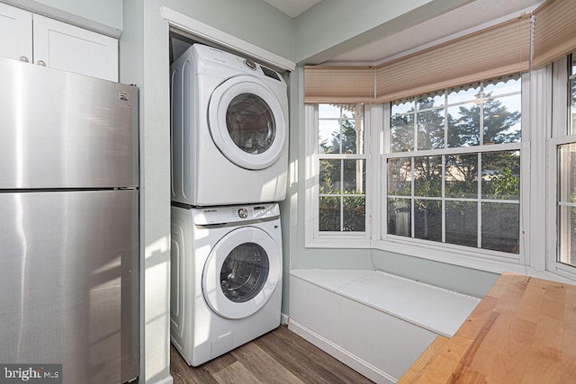 laundry area featuring stacked washing maching and dryer and dark hardwood / wood-style floors