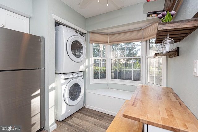 laundry room featuring ceiling fan, wood-type flooring, and stacked washing maching and dryer