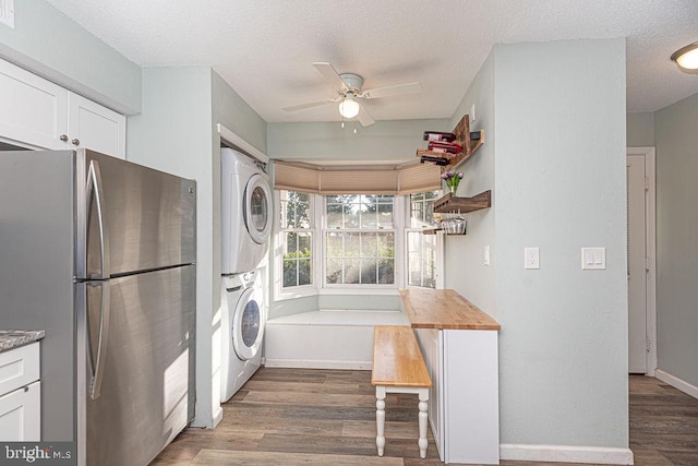 kitchen with stainless steel refrigerator, stacked washer / dryer, dark hardwood / wood-style floors, and white cabinets