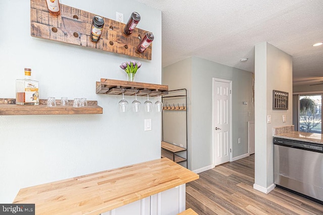 kitchen featuring wood-type flooring, stainless steel dishwasher, and a textured ceiling