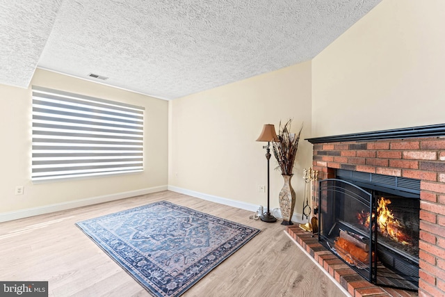 sitting room with hardwood / wood-style flooring, a fireplace, and a textured ceiling