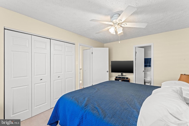 bedroom featuring ceiling fan, light colored carpet, a textured ceiling, and a closet