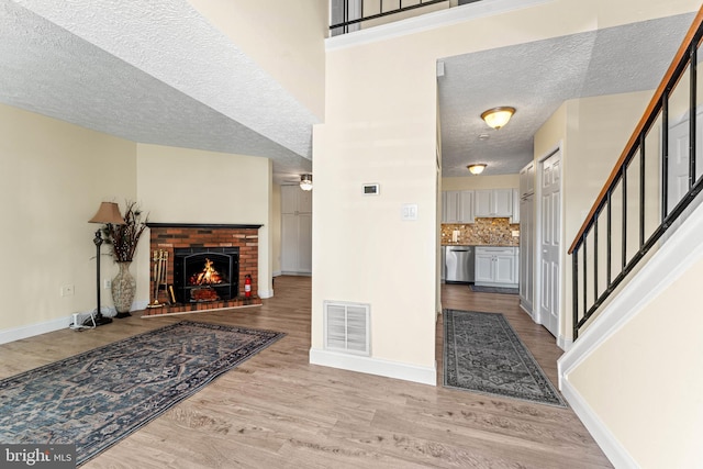 foyer featuring ceiling fan, a fireplace, light hardwood / wood-style flooring, and a textured ceiling