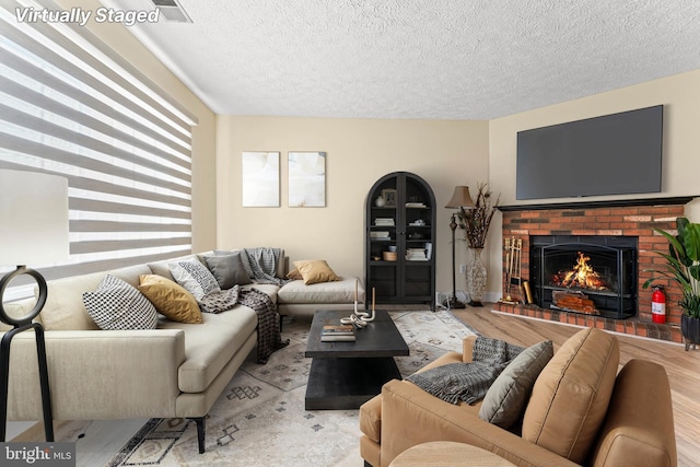 living room with a textured ceiling, a fireplace, and light hardwood / wood-style flooring