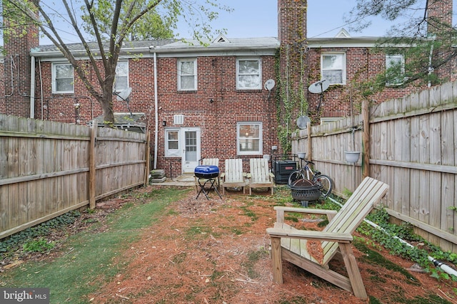 rear view of property featuring brick siding and a fenced backyard