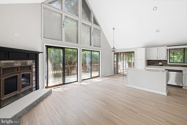 unfurnished living room with light hardwood / wood-style flooring, a fireplace, and high vaulted ceiling