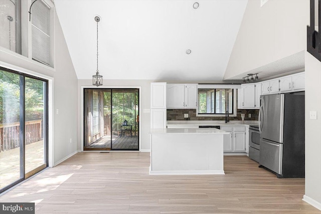 kitchen with white cabinetry, high vaulted ceiling, hanging light fixtures, appliances with stainless steel finishes, and decorative backsplash