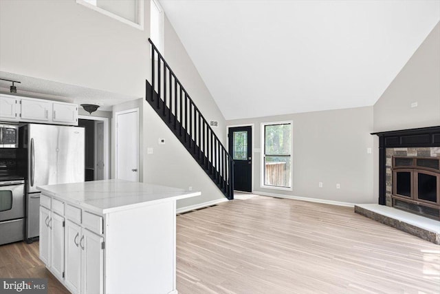 kitchen with light stone counters, light hardwood / wood-style flooring, appliances with stainless steel finishes, a kitchen island, and white cabinets