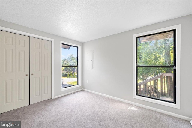 unfurnished bedroom with light carpet, a textured ceiling, and a closet