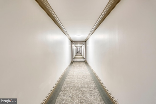 hall with dark colored carpet and ornamental molding