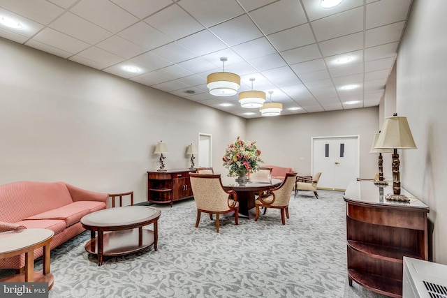 carpeted dining area featuring a paneled ceiling